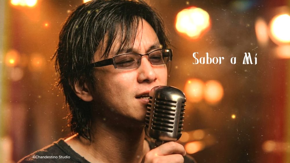 《Sabor a Mí》MV 封面：陳子詠喺暖色燈光下對住復古咪唱歌